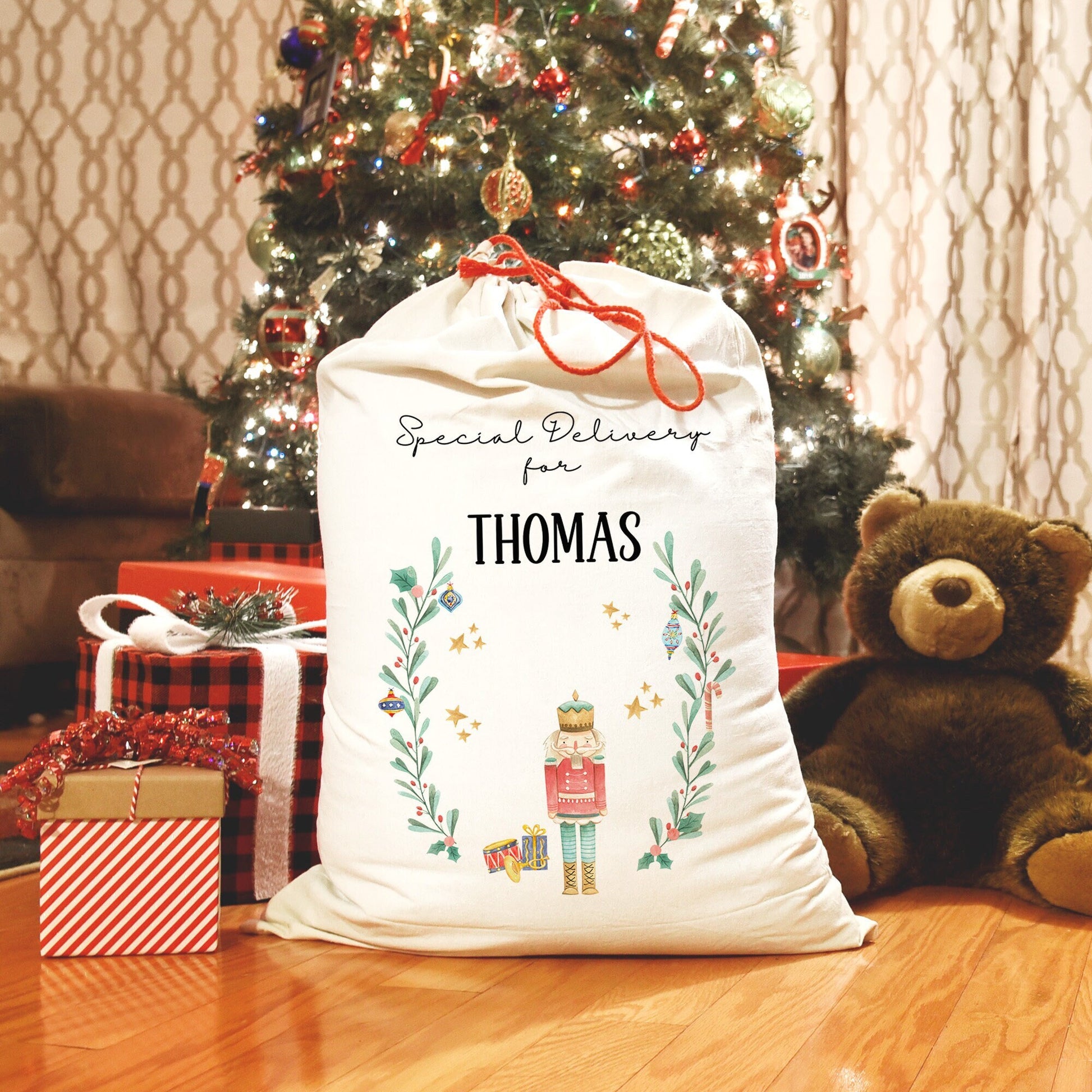 christmas santa sack for presents with a watercolour nutcracker design and hollywreath, festive decor personalised with name of choice, linen, with red drawstrings