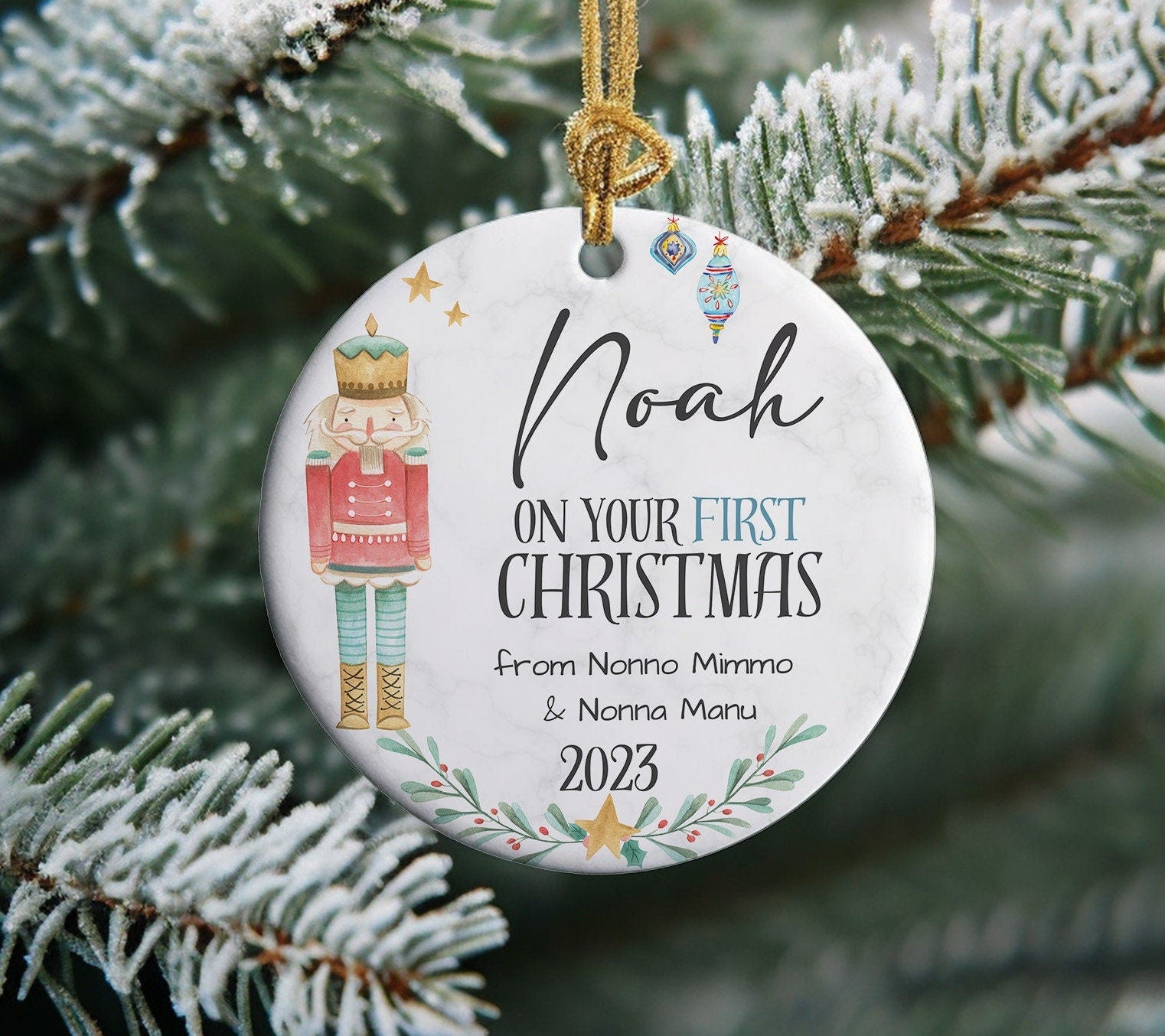 a round ceramic ornament with light white and grey marble background picturing a vintage nutcracker and the child&#39;s name in handwritten black font. itcan be personalised with a message printed and the year